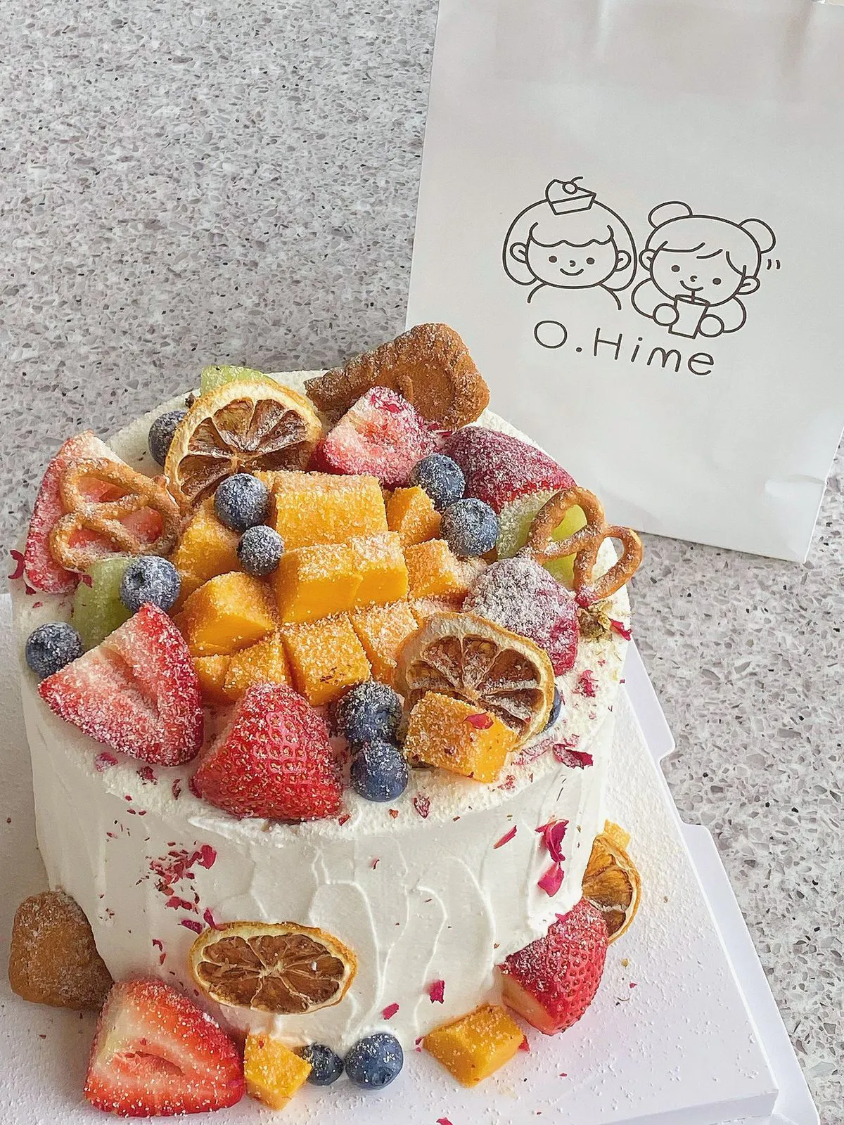 White cream fruit cake topped with mango, strawberry, blueberry and cookies at O.Hime Cake, a Bakery in Waterloo