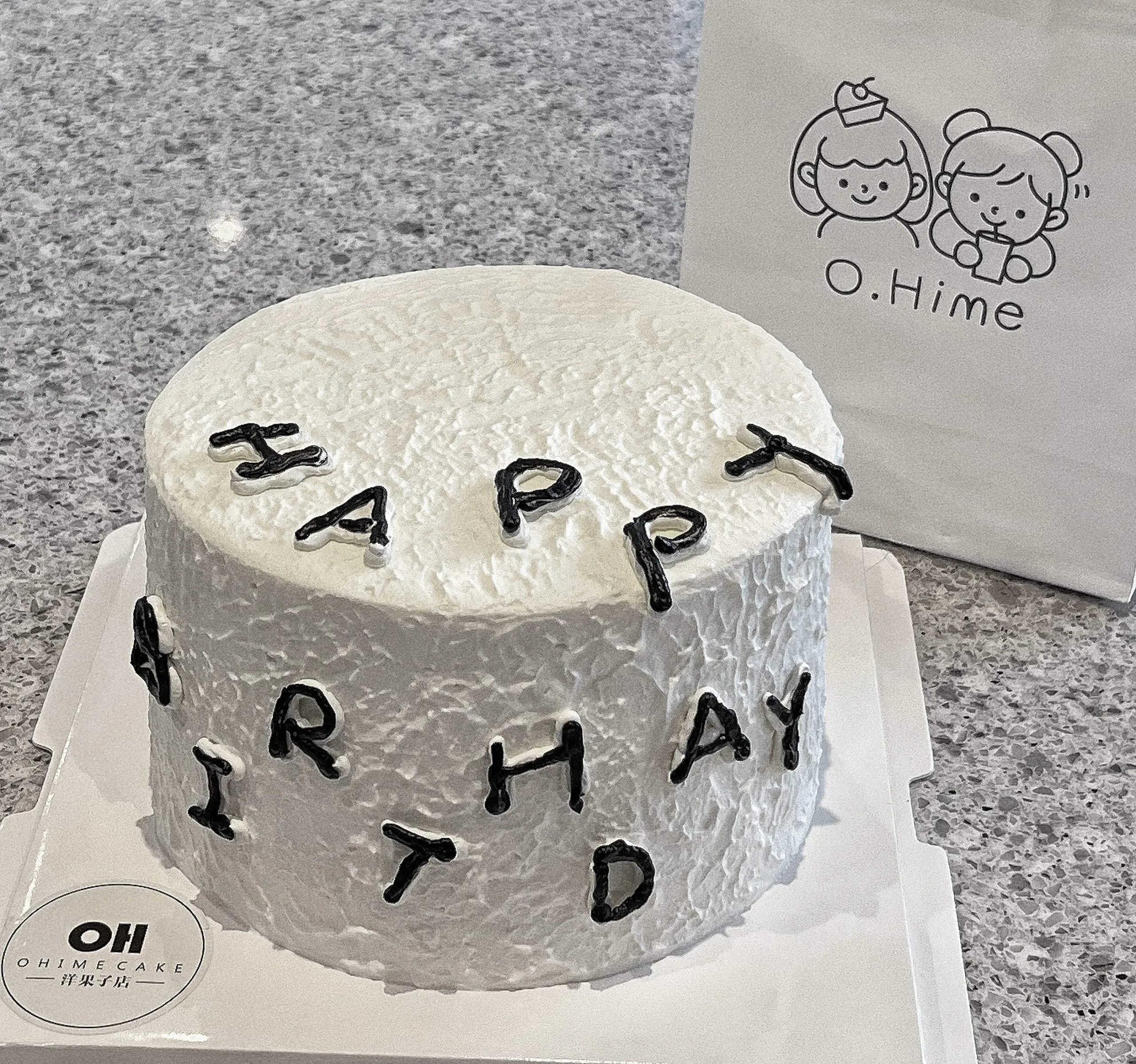 Minimalist white textured birthday cake with black letter decor at O.Hime Cake, a Bakery in Waterloo